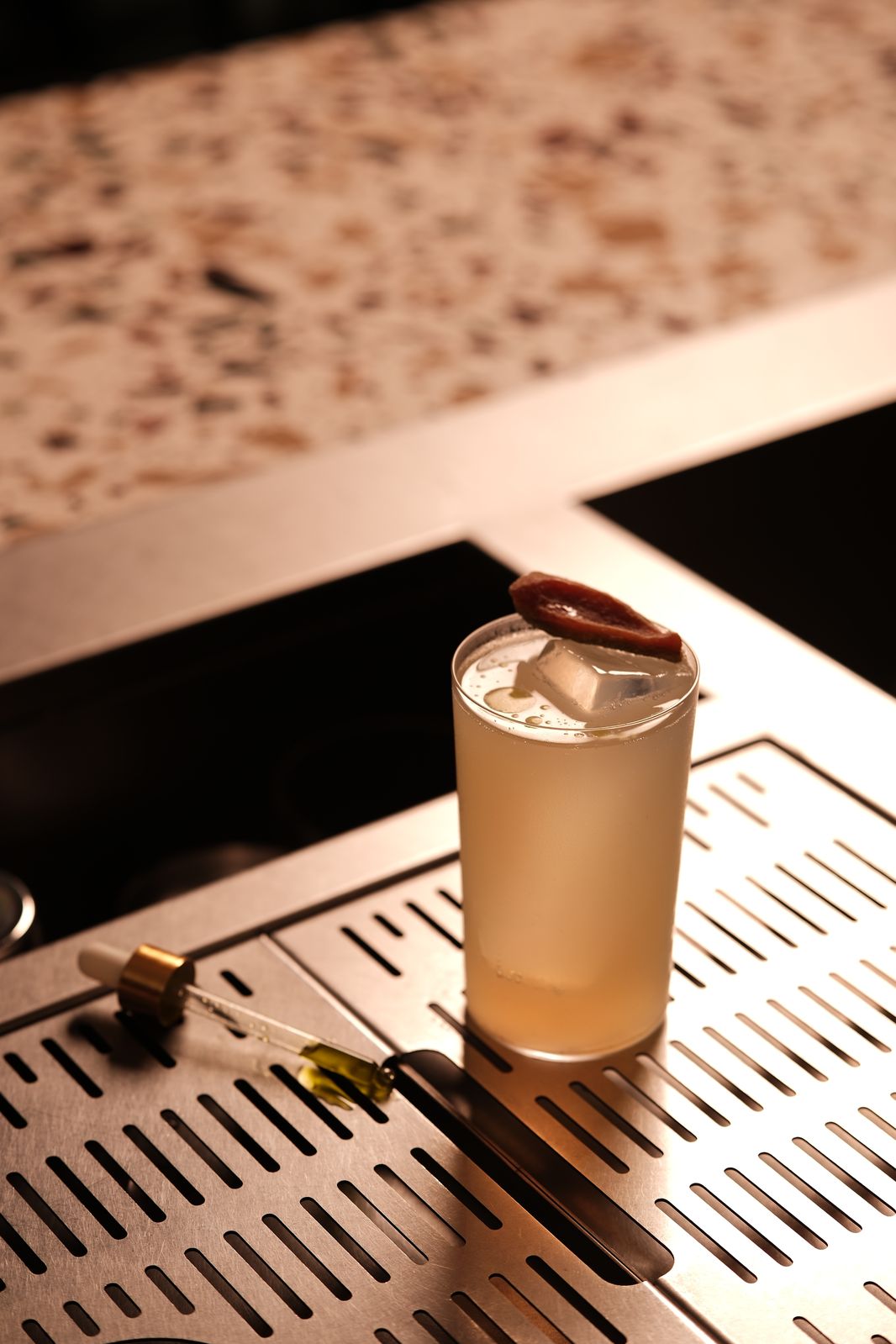 A highball garnished with a dried fruit slice on the Rembar bar counter