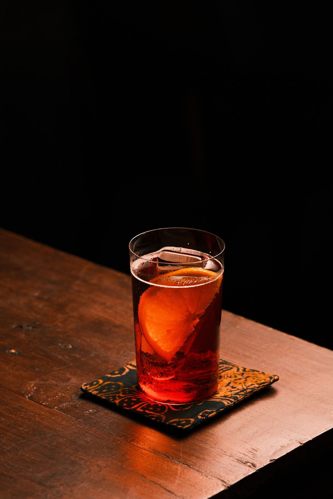 A dark spirit-forward cocktail with orange garnish at Rembar