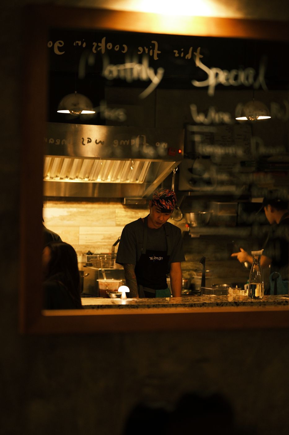 A cook working at the pass under the kitchen signage