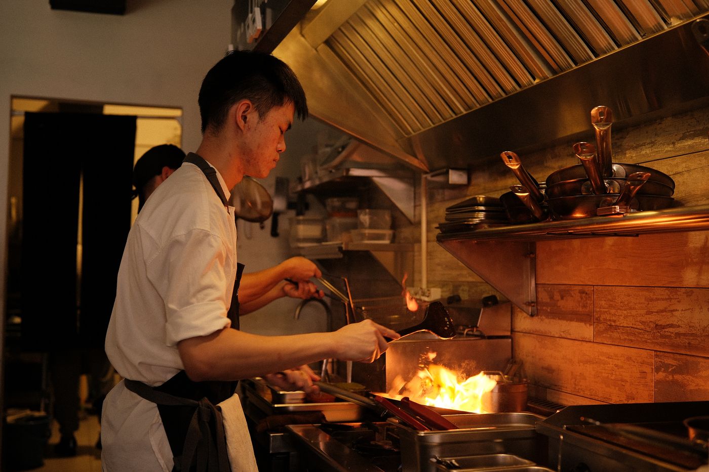 A cook working the flame at the Rembar kitchen line
